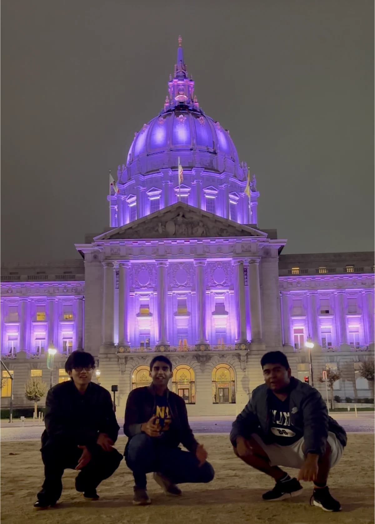 Three Brain Brew participants in front of San Francisco City Hall illuminated purple at night